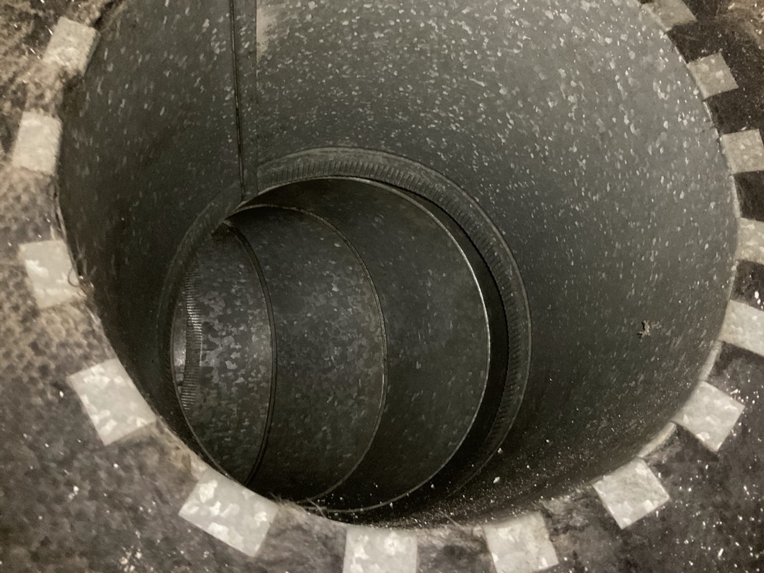 Round metal damper flap inside ductwork during inspection