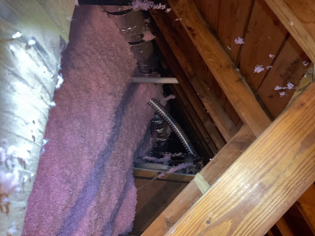 Fiberglass insulation batts installed between attic floor joists in Del City home.