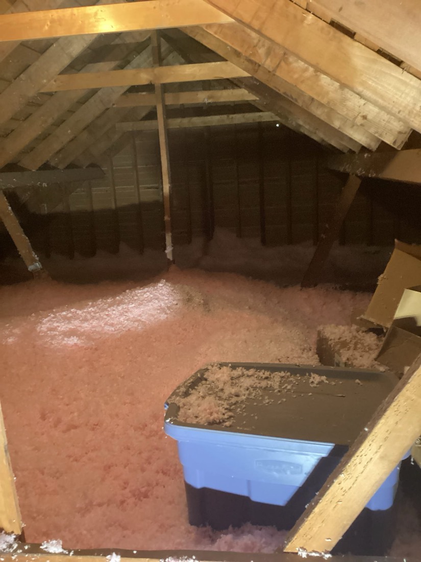 Attic with newly installed pink fiberglass insulation across floor