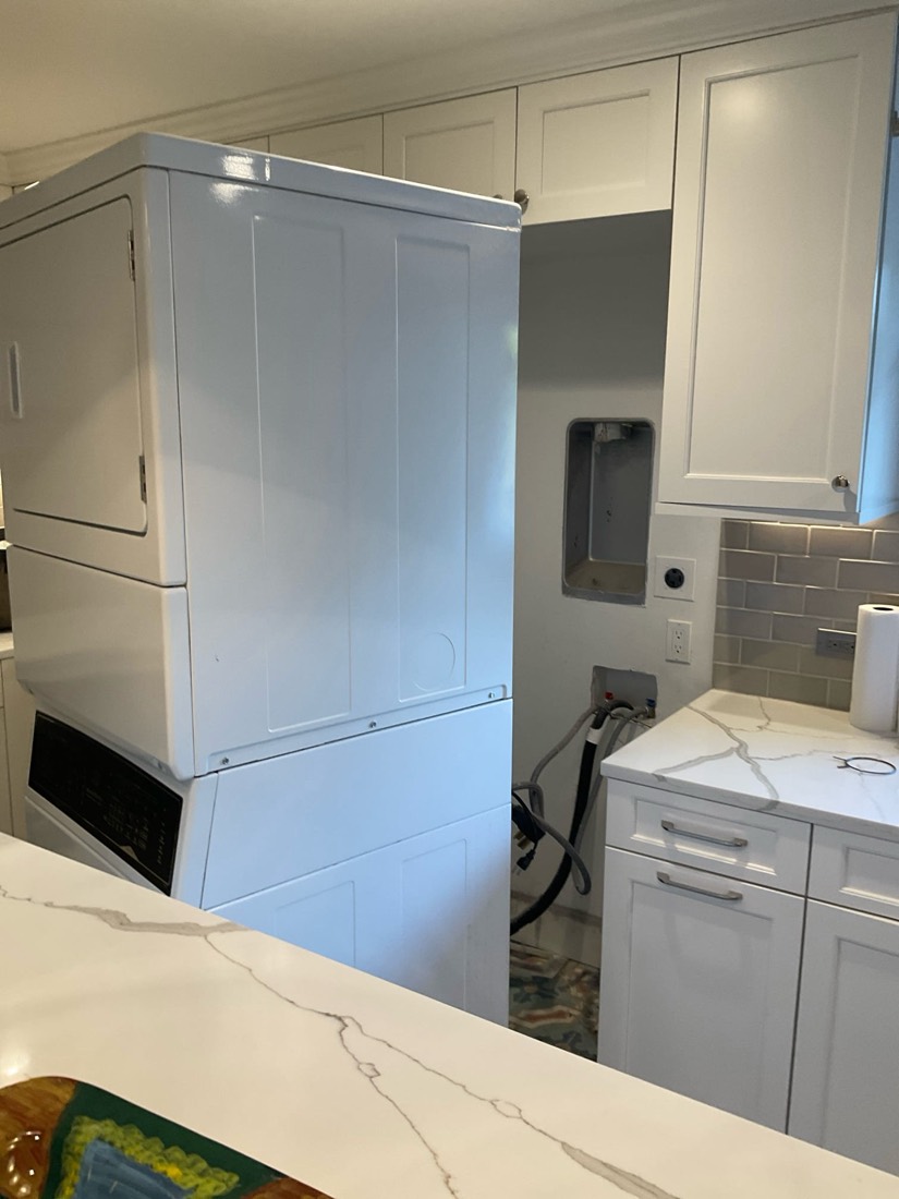 Tall dryer machine installed in laundry area next to bathroom vanity