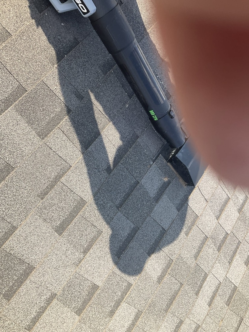 Dryer vent cleaning tool on roof with shingle pattern visible