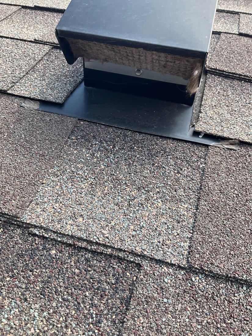 Black roof vent box installed on shingled roof.
