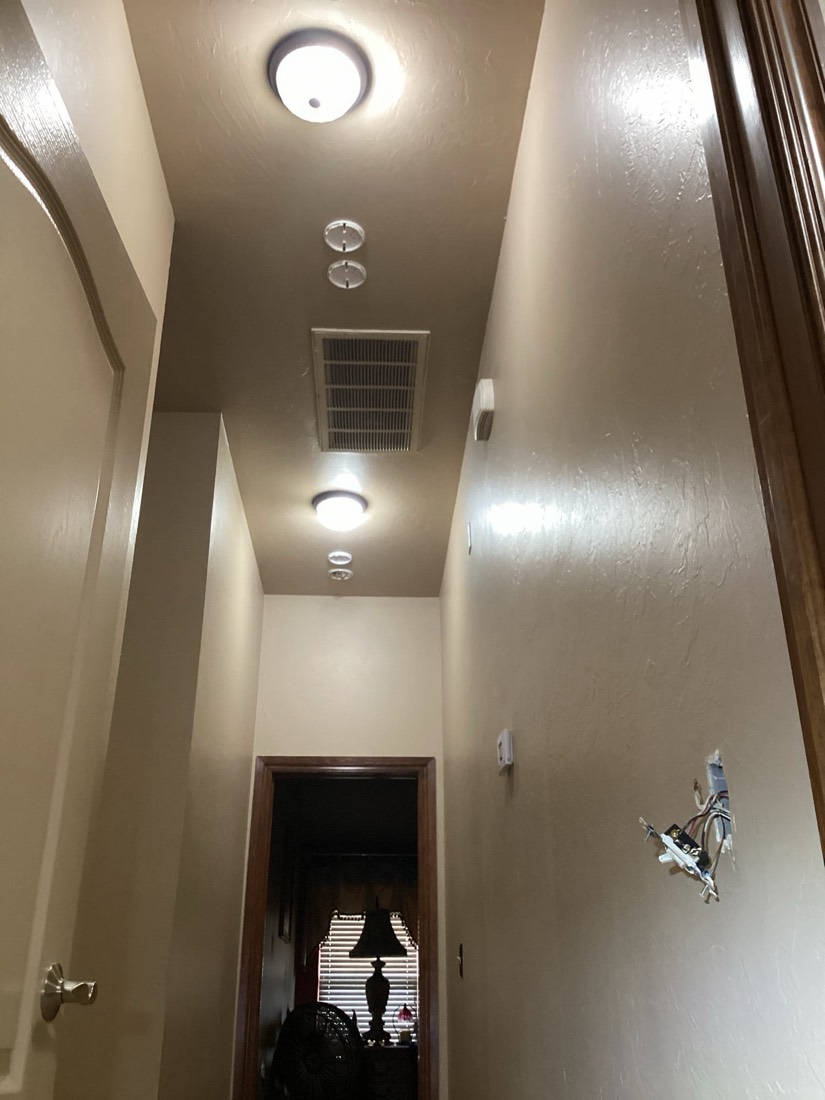 Recessed ceiling lights and ventilation duct in hallway.