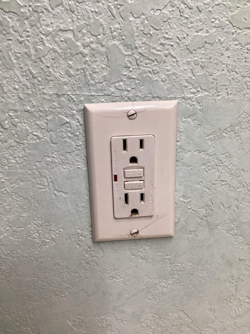 Newly installed GFCI electrical outlet on wall.