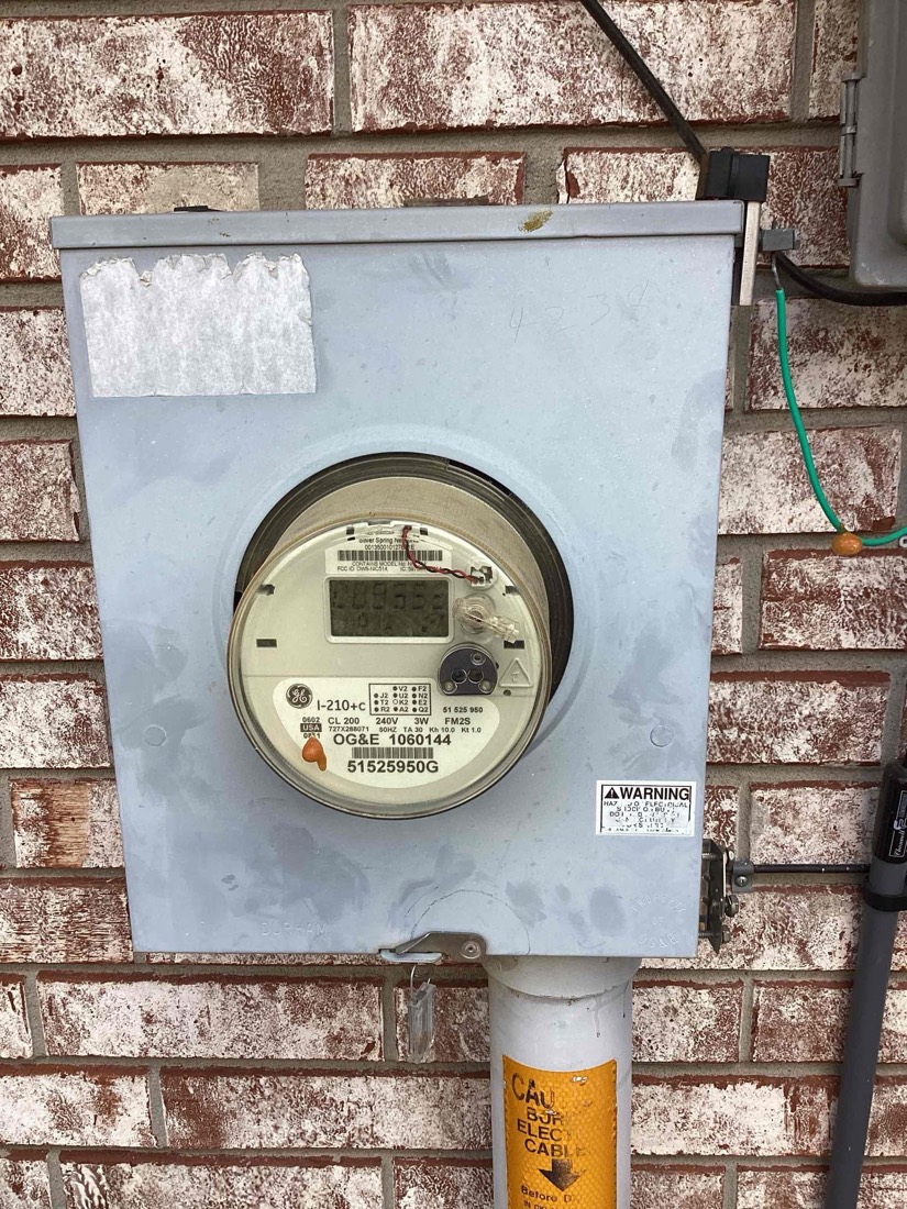 Close-up of new electrical meter mounted on brick wall.