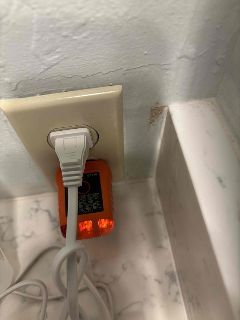 White GFI outlet with orange indicator lights mounted in wall plate.