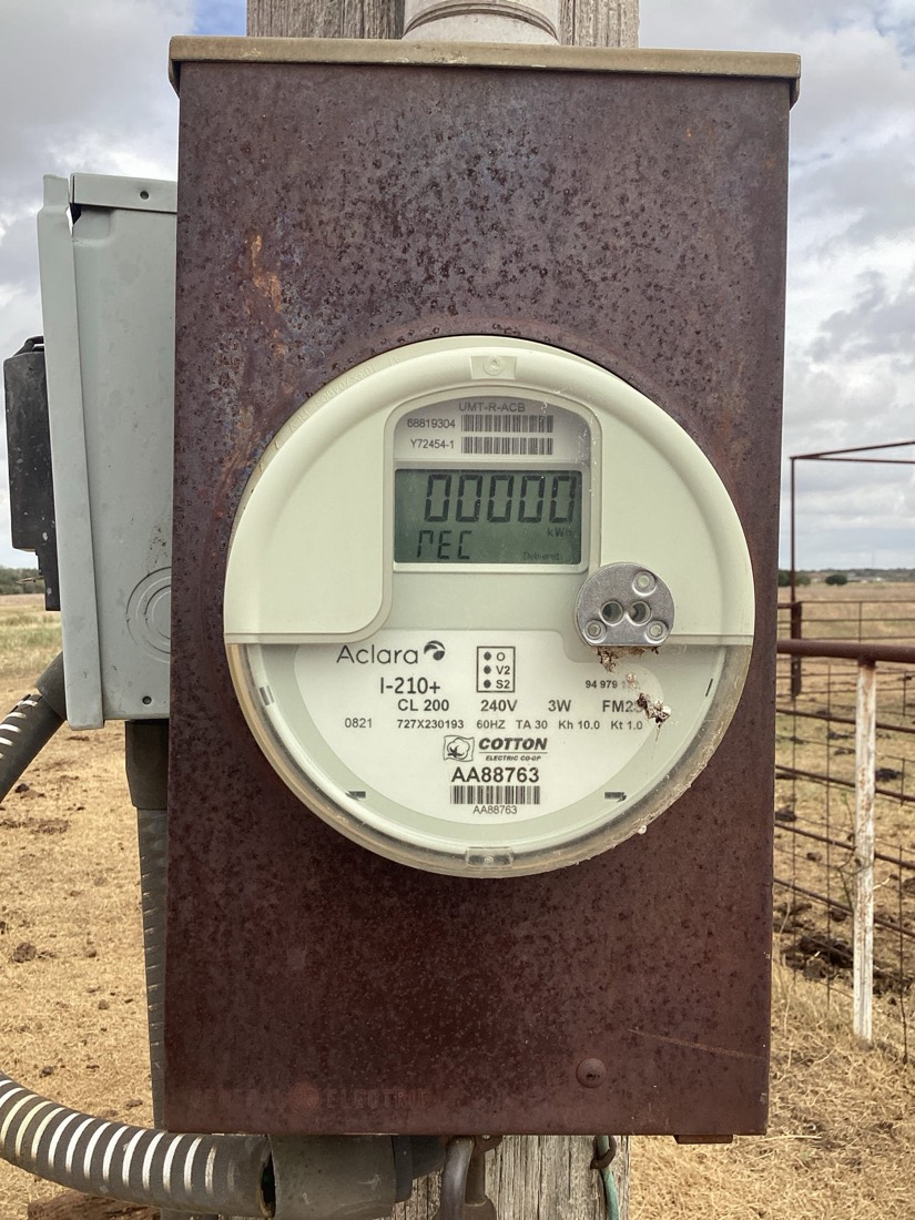 Aclara electricity meter mounted on weathered metal enclosure with disconnect switch