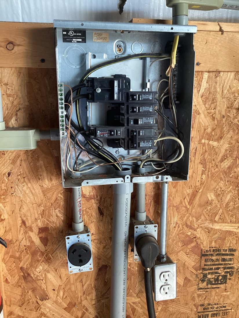 Main electrical panel with breakers, conduit, and outlets installed on wooden backing