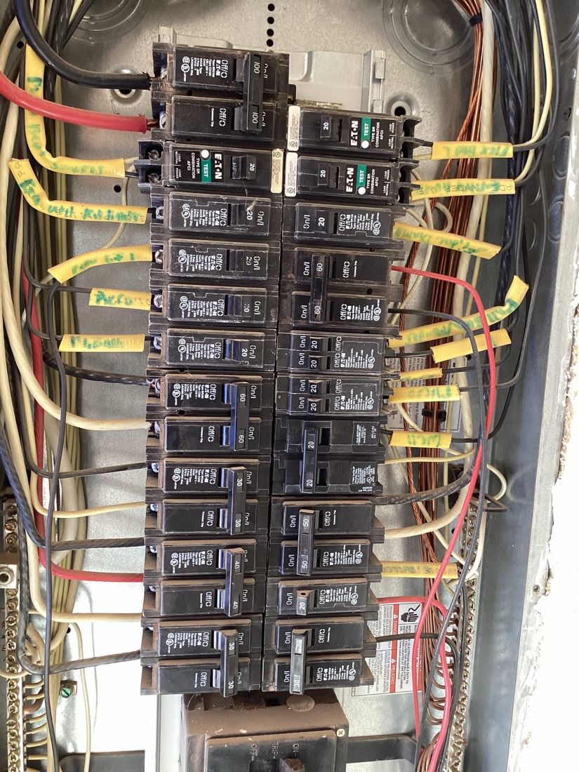 Organized electrical panel with circuit breakers and yellow labeled wiring