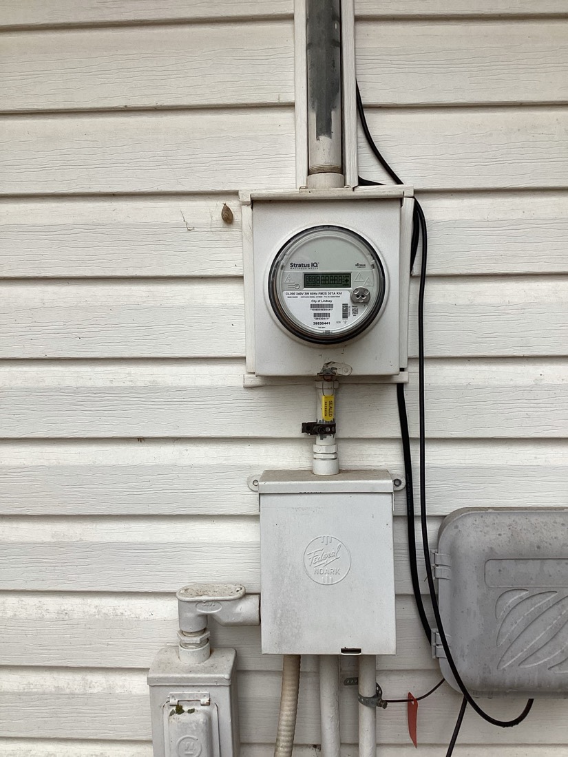 Newly installed electrical meter mounted on exterior home wall with wiring