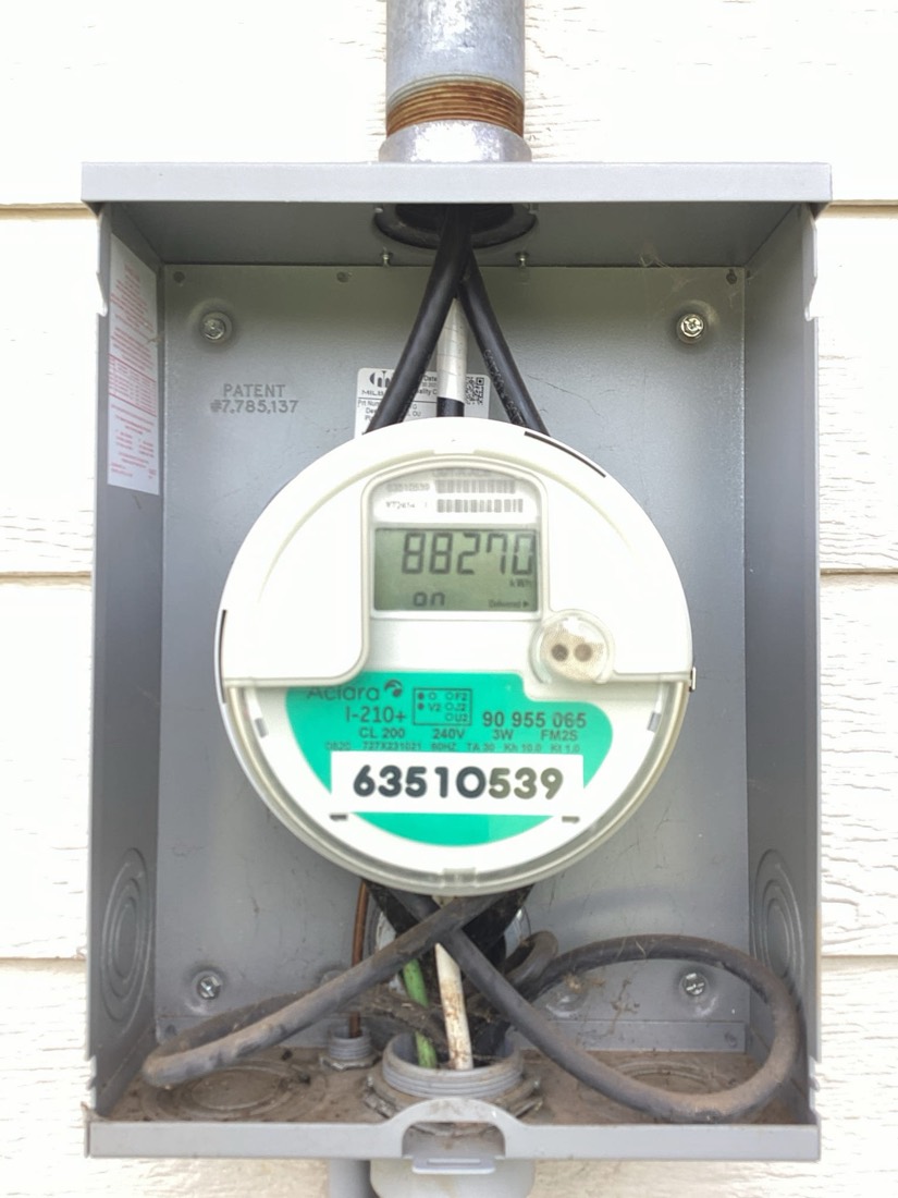 Electric meter mounted on house exterior.