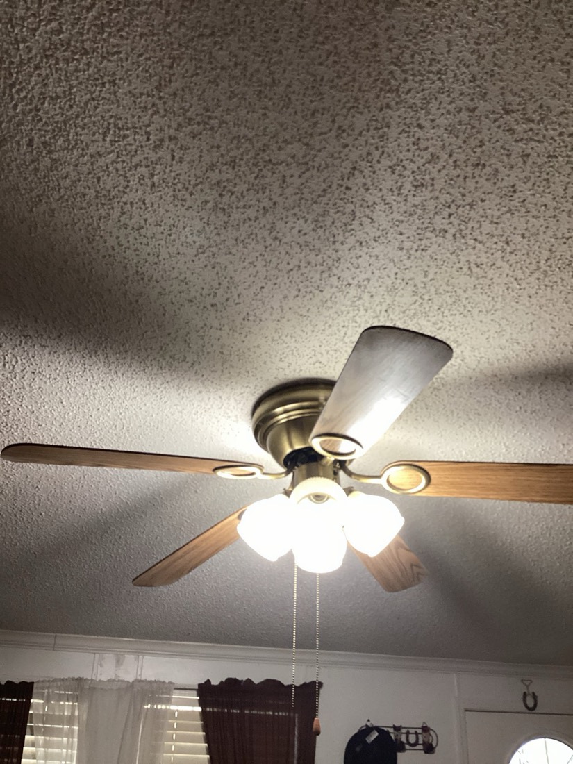 Installed ceiling fan with light kit and wooden blades on white ceiling.