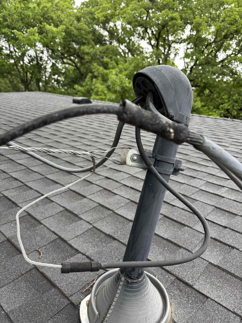 Electrical service head with conduit and mast on shingled roof.