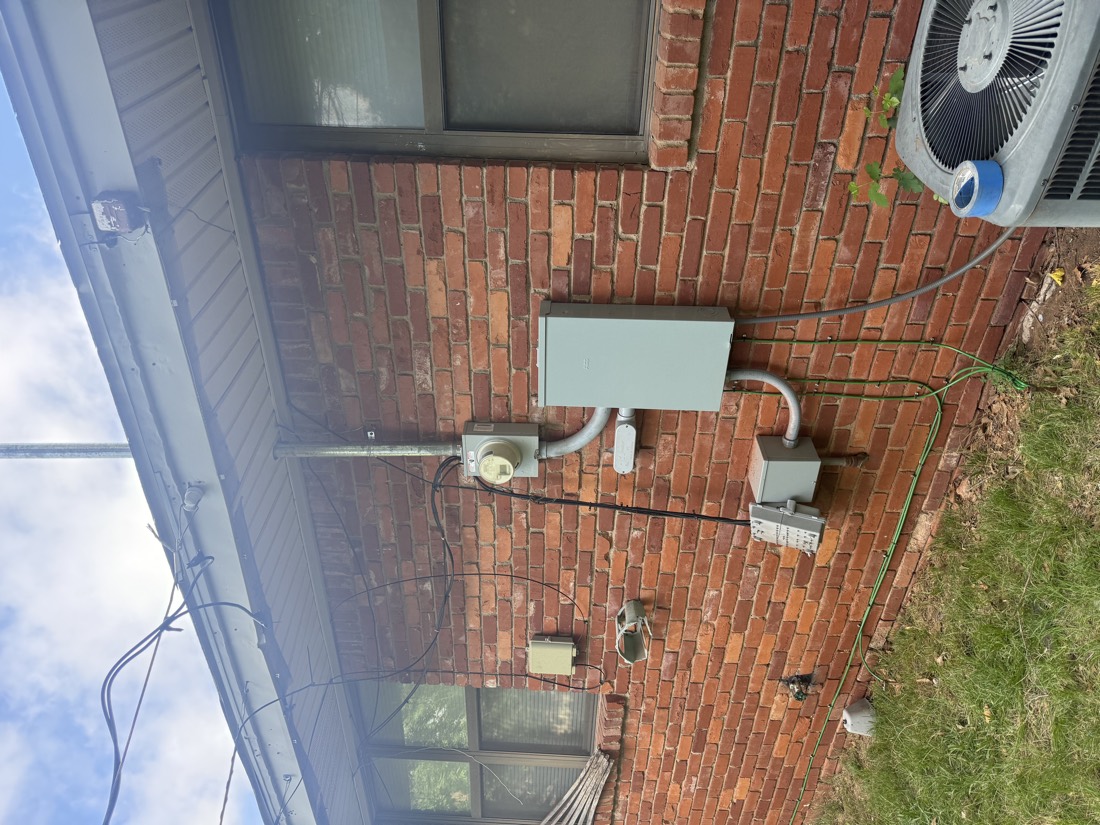 Electrical service panel with conduit on brick wall