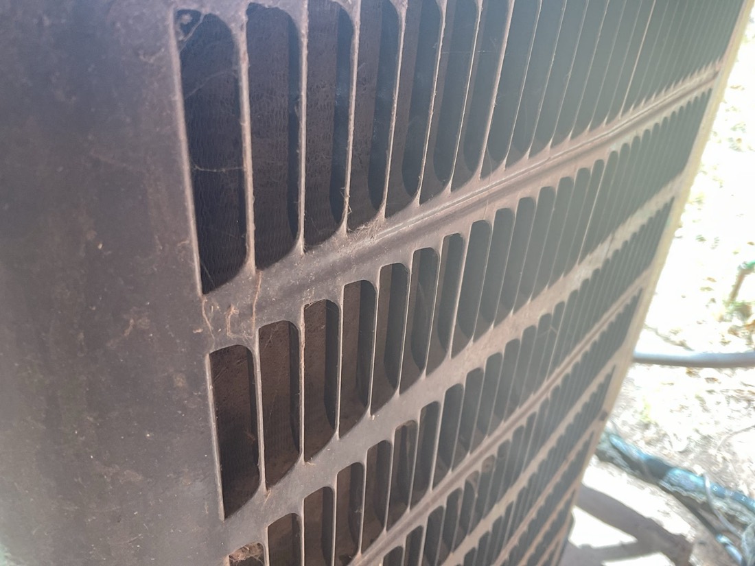 AC condenser front grille showing aluminum fins and vents.