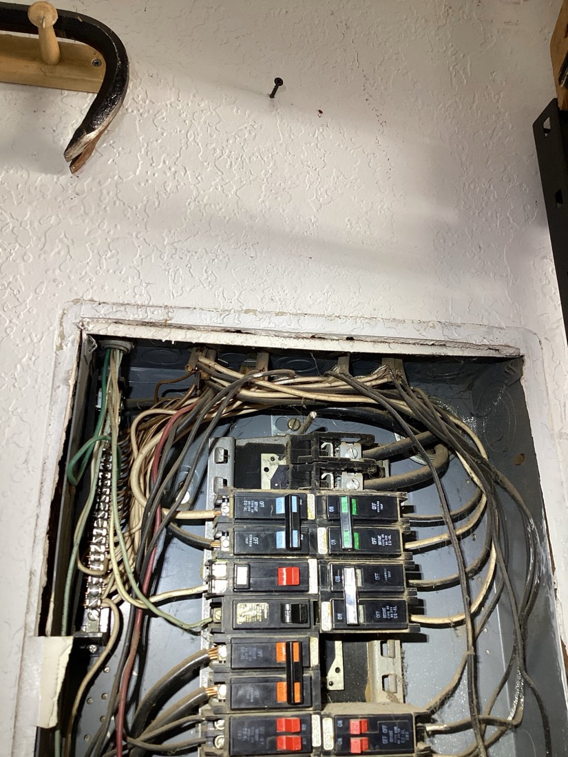 Interior main electrical panel with circuit breakers and colored wires.