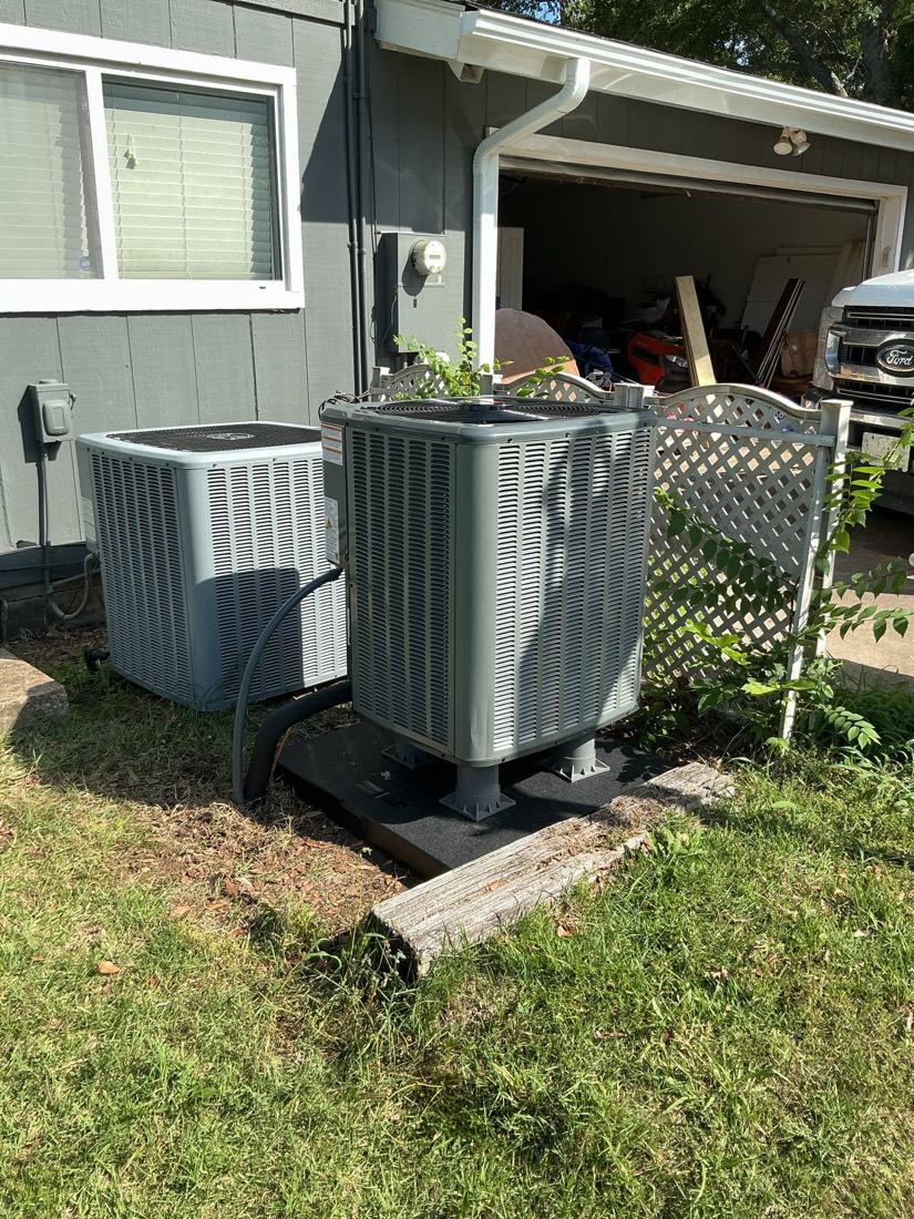 Installed AC condenser units on concrete pad by home