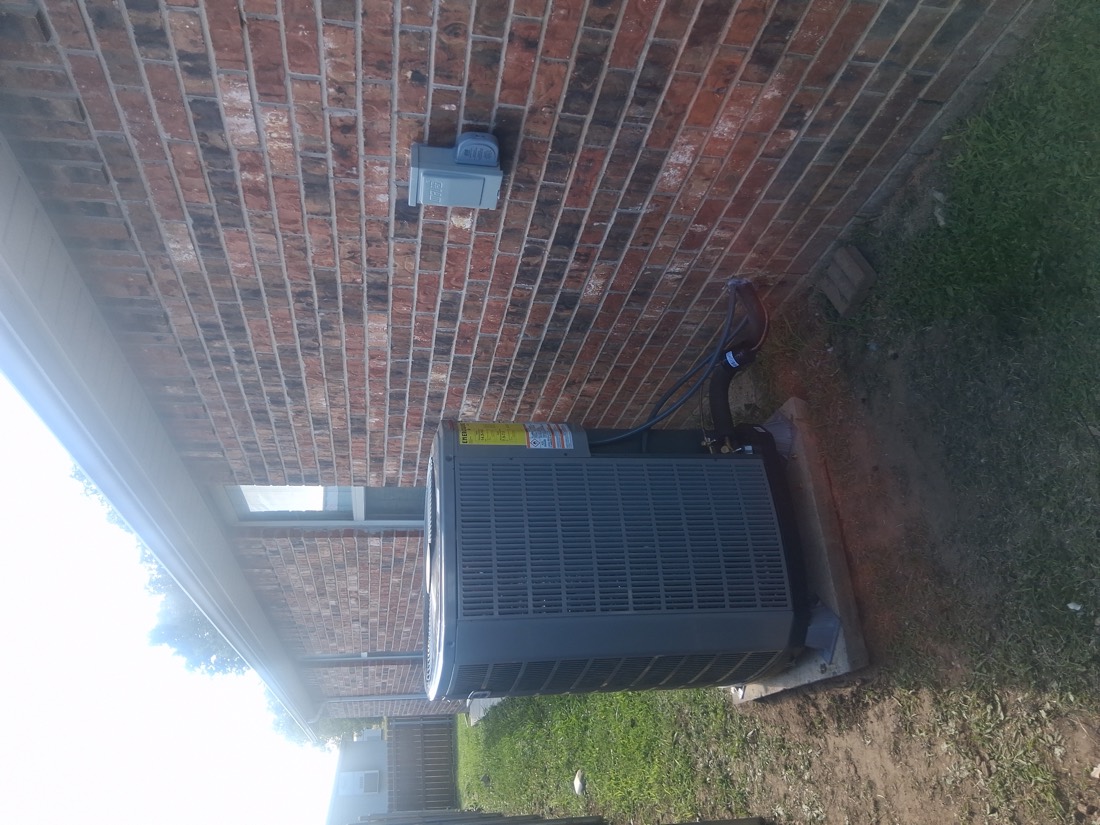 AC condenser unit installed on brick home foundation