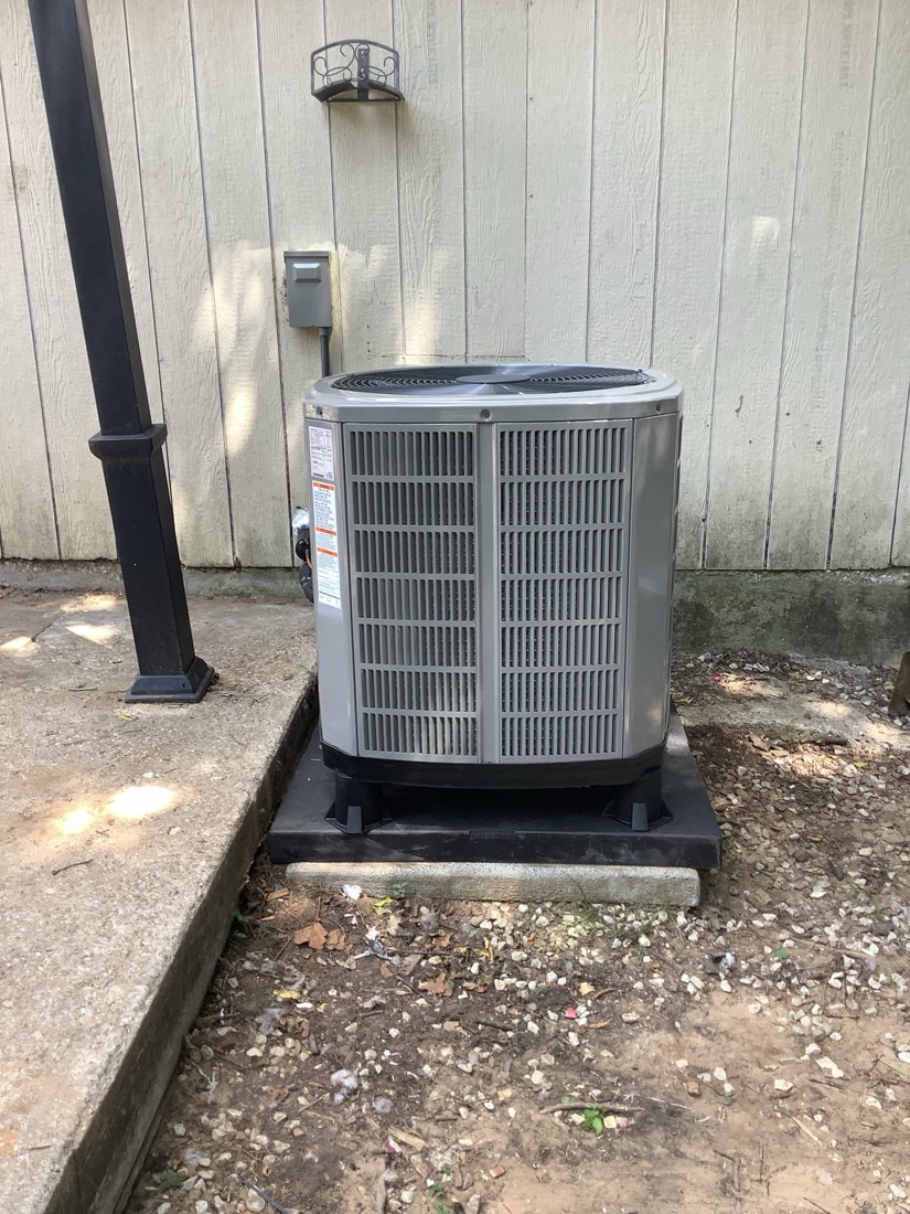 Newly installed condenser unit on concrete pad with disconnect