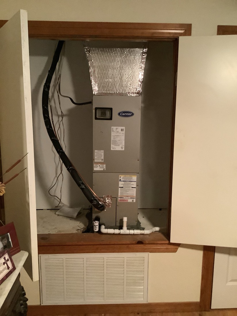 Installed Carrier HVAC unit with duct connections in wall cavity