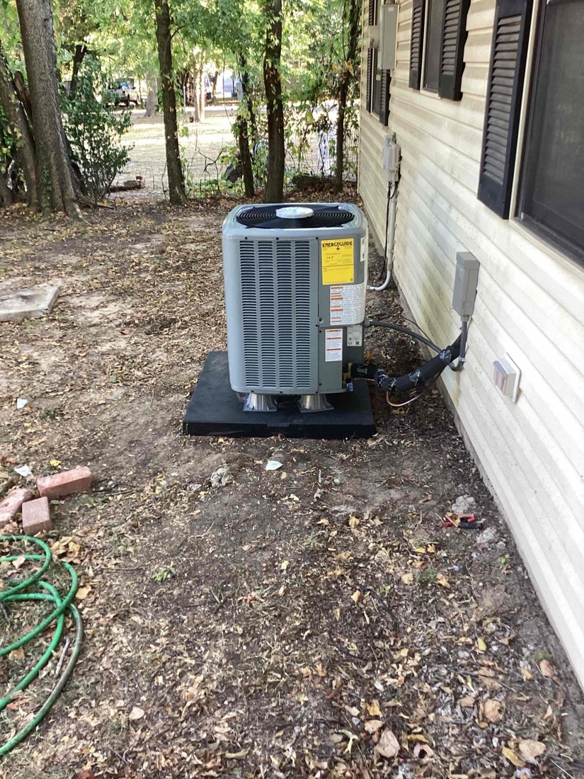 AC condenser unit on black pad next to house exterior