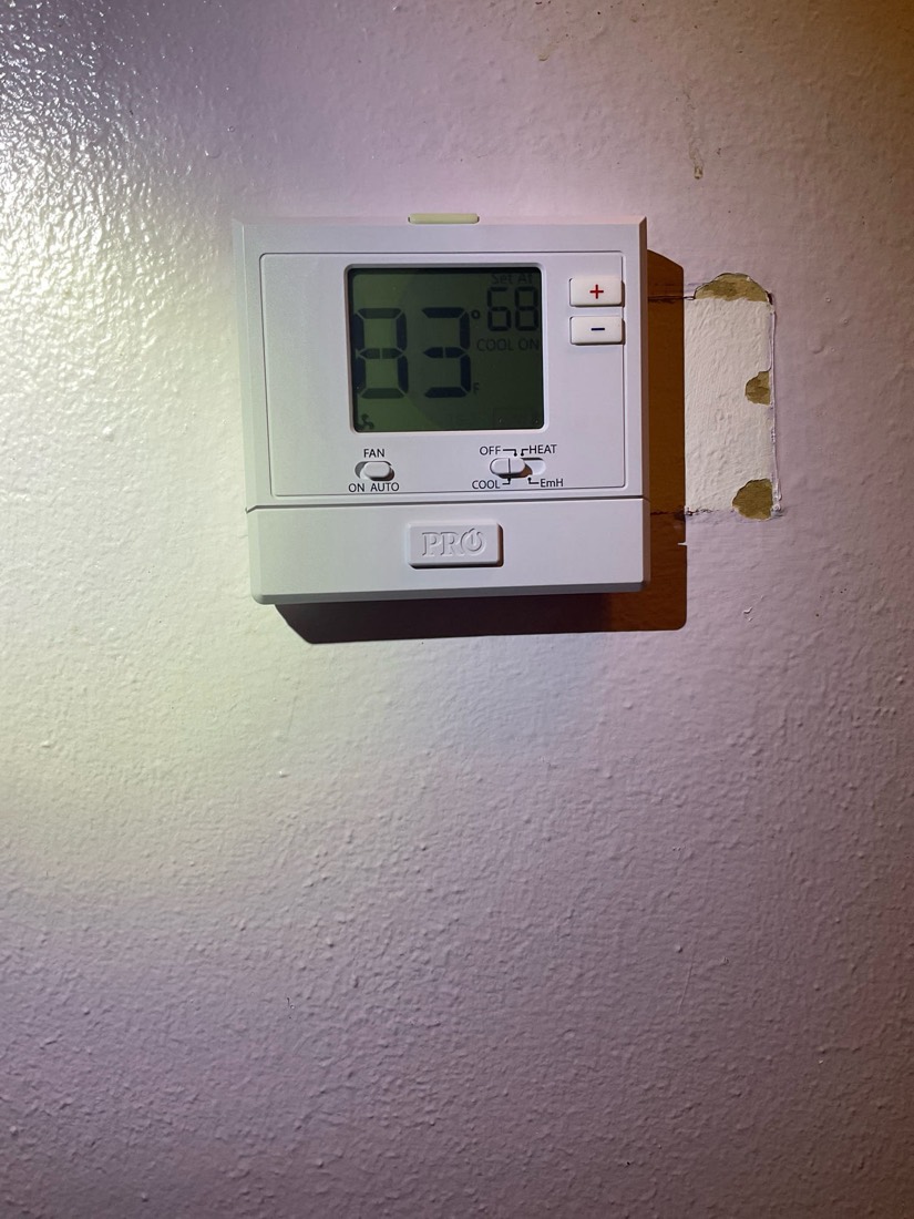 Wall-mounted thermostat displaying temperature setting