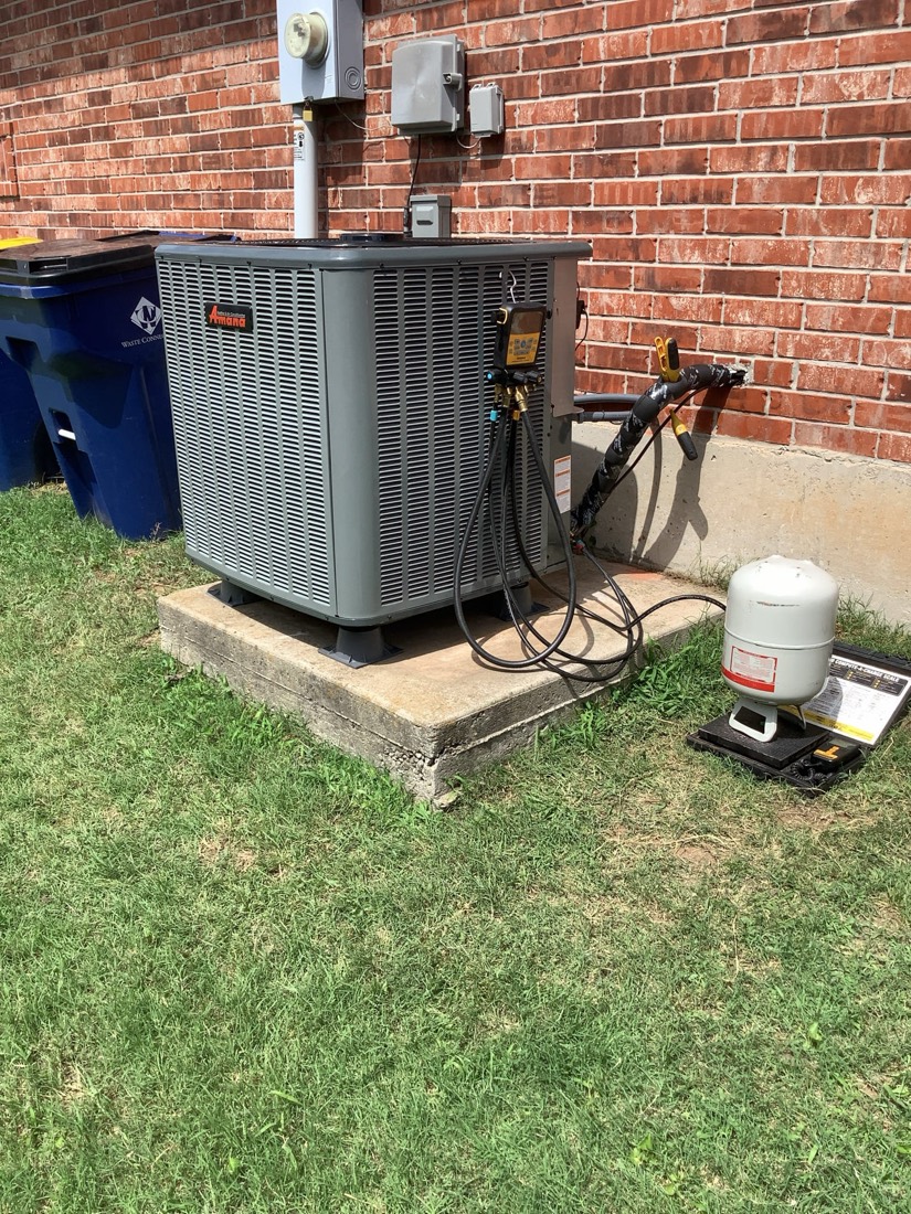 Outdoor AC condenser unit on pad with disconnected lines and gauge