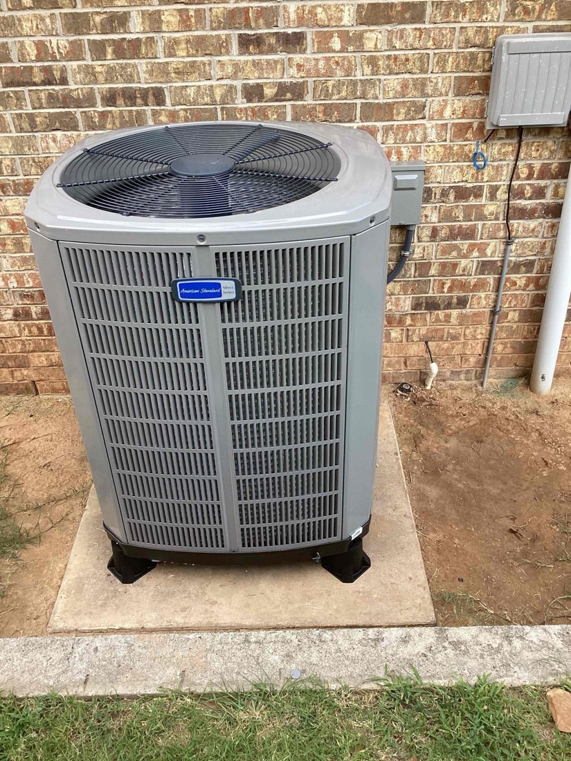 AC condenser unit installed with refrigerant lines connected to brick home.