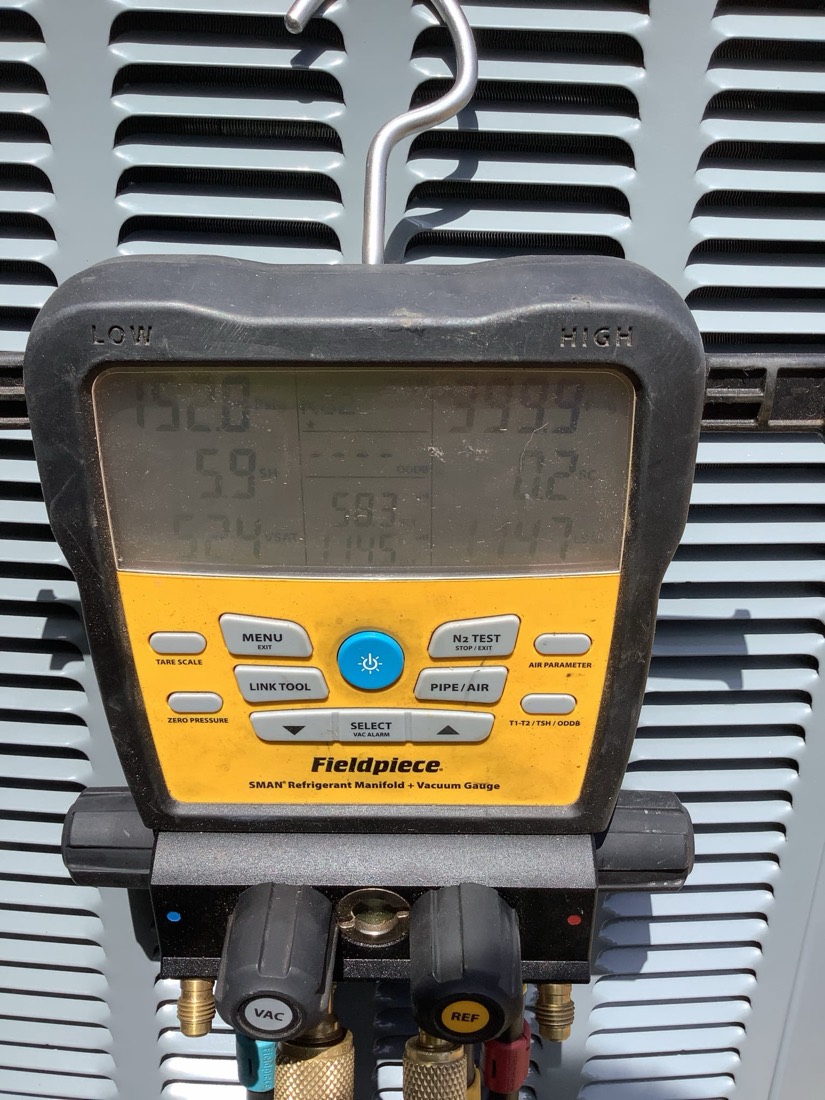 Digital refrigerant manifold gauge showing pressure readings during AC service.