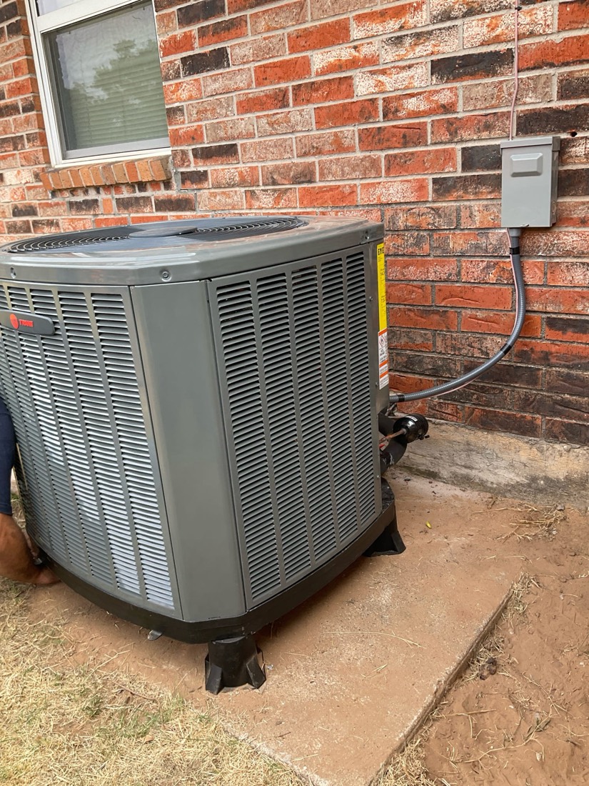 Installed AC condenser with yellow cable connection and black standoffs.