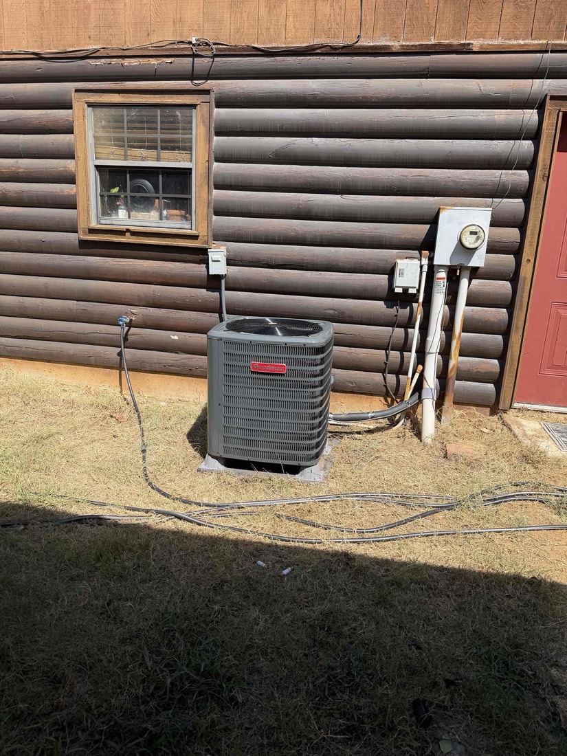 Installed outdoor HVAC air conditioning unit against log cabin