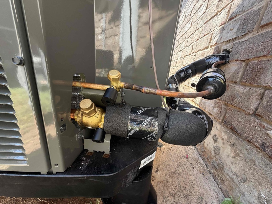 Copper refrigerant lines with brass ball valves on outdoor unit