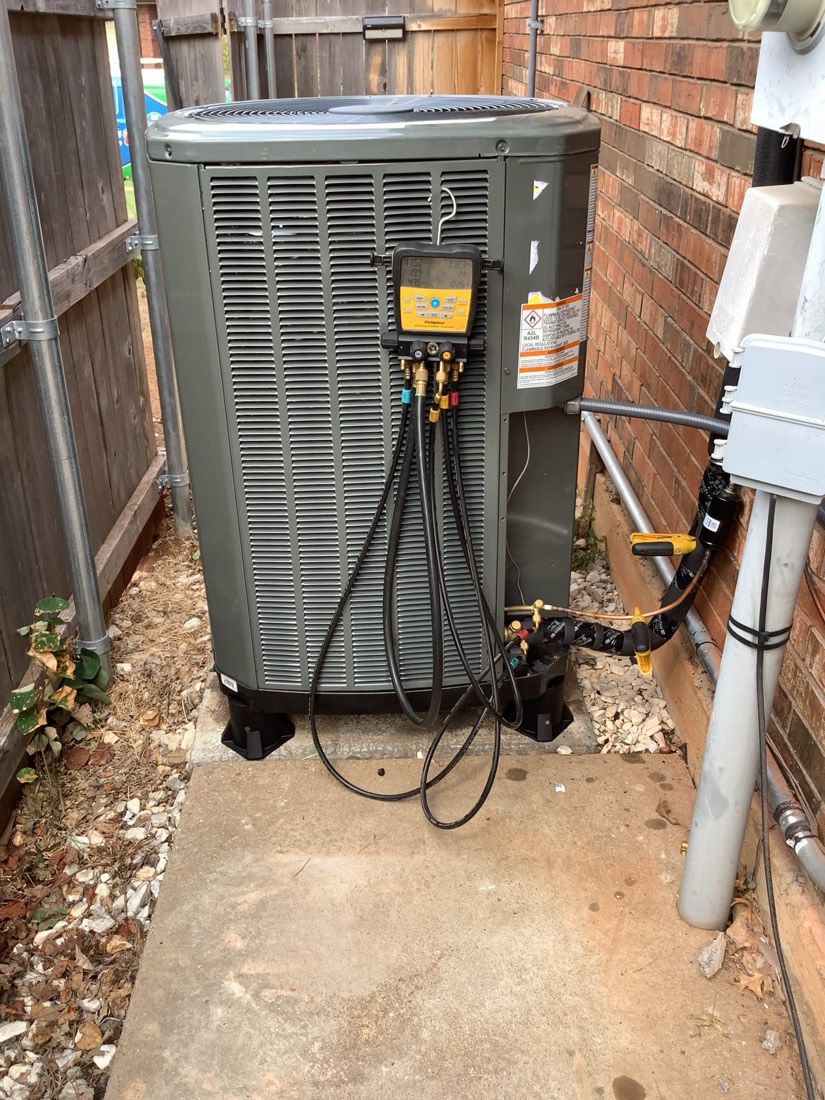 New AC unit with service gauges, copper lines, and electrical connections installed outdoors.