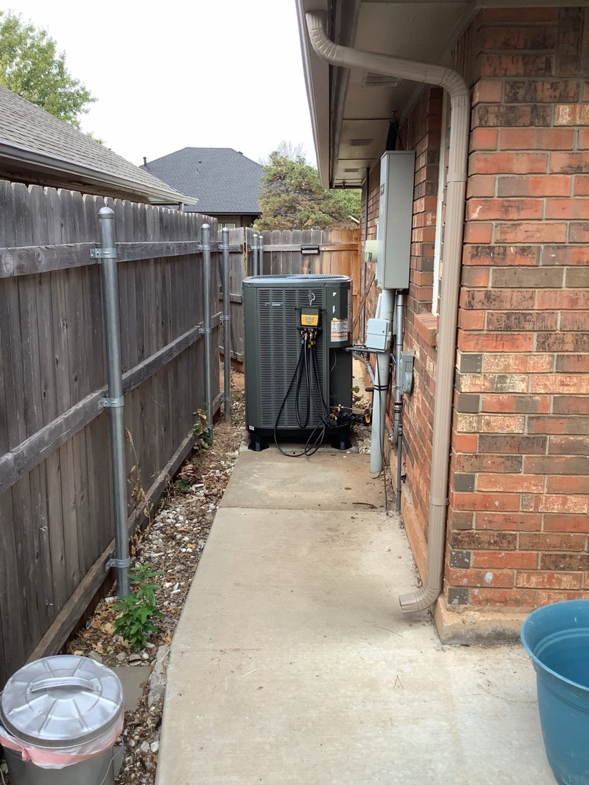 Installed AC unit with piping and electrical connections in outdoor enclosure.