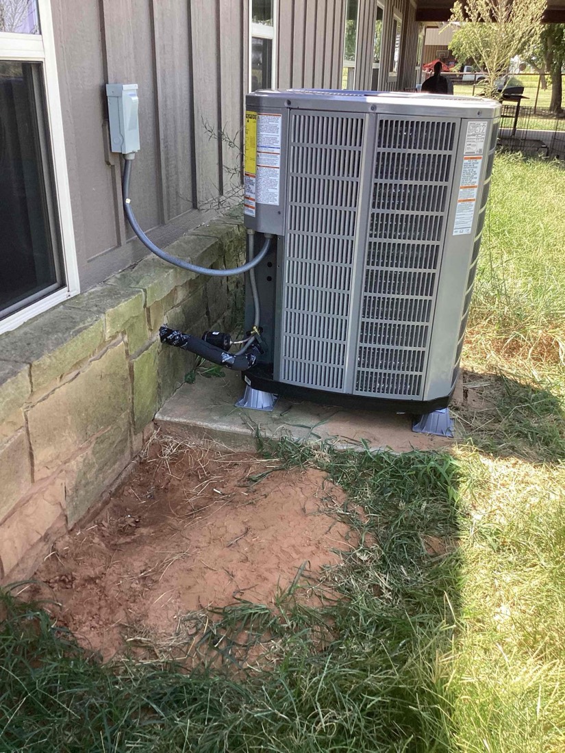Freshly installed outdoor AC condenser unit with refrigerant lines connected.