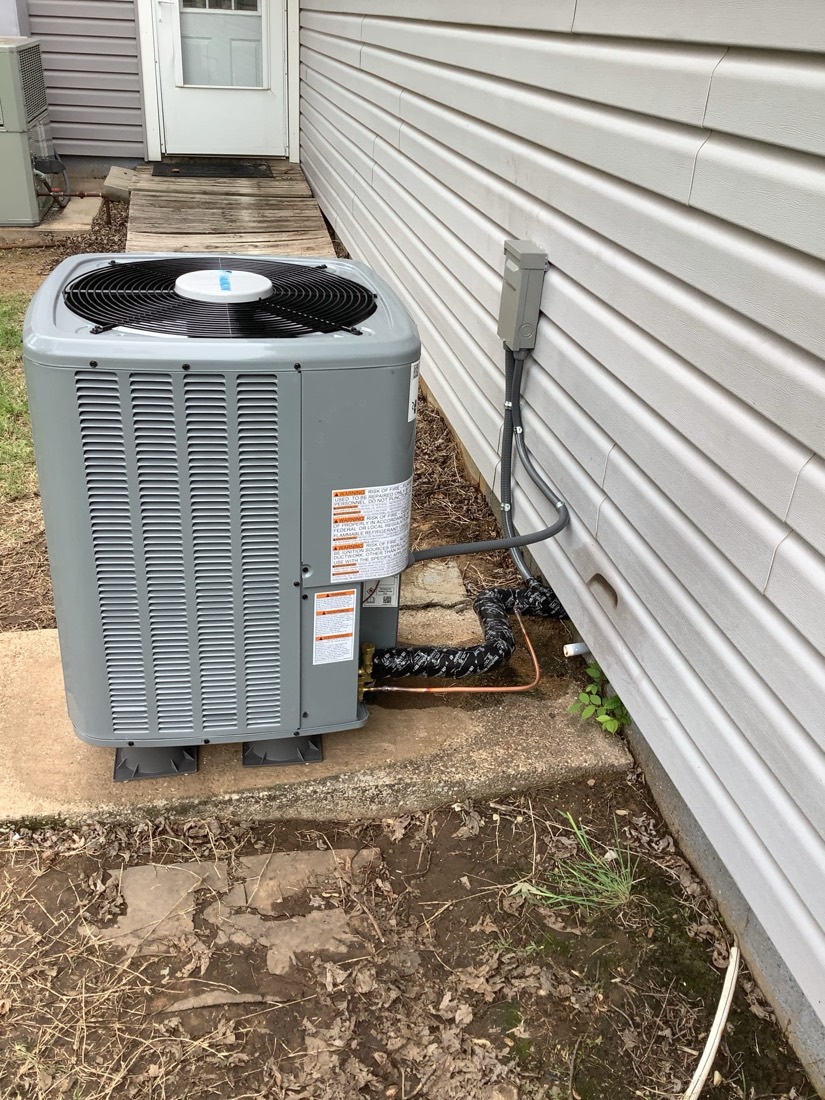 Gray air conditioning condenser unit installed next to house exterior