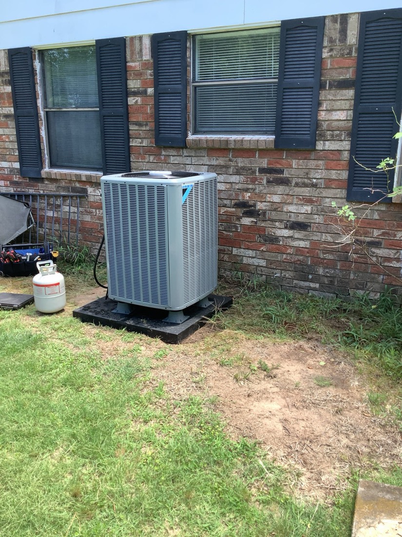 Clean Daikin outdoor AC condenser unit on concrete mounting pad.