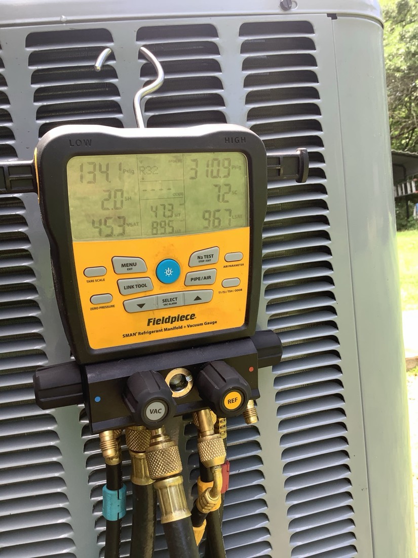 Fieldpiece manifold gauge showing temperature and pressure readings on outdoor AC unit.