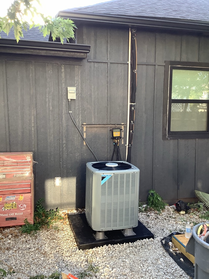 Newly installed Daikin air conditioning unit on outdoor pad with connected refrigerant lines.