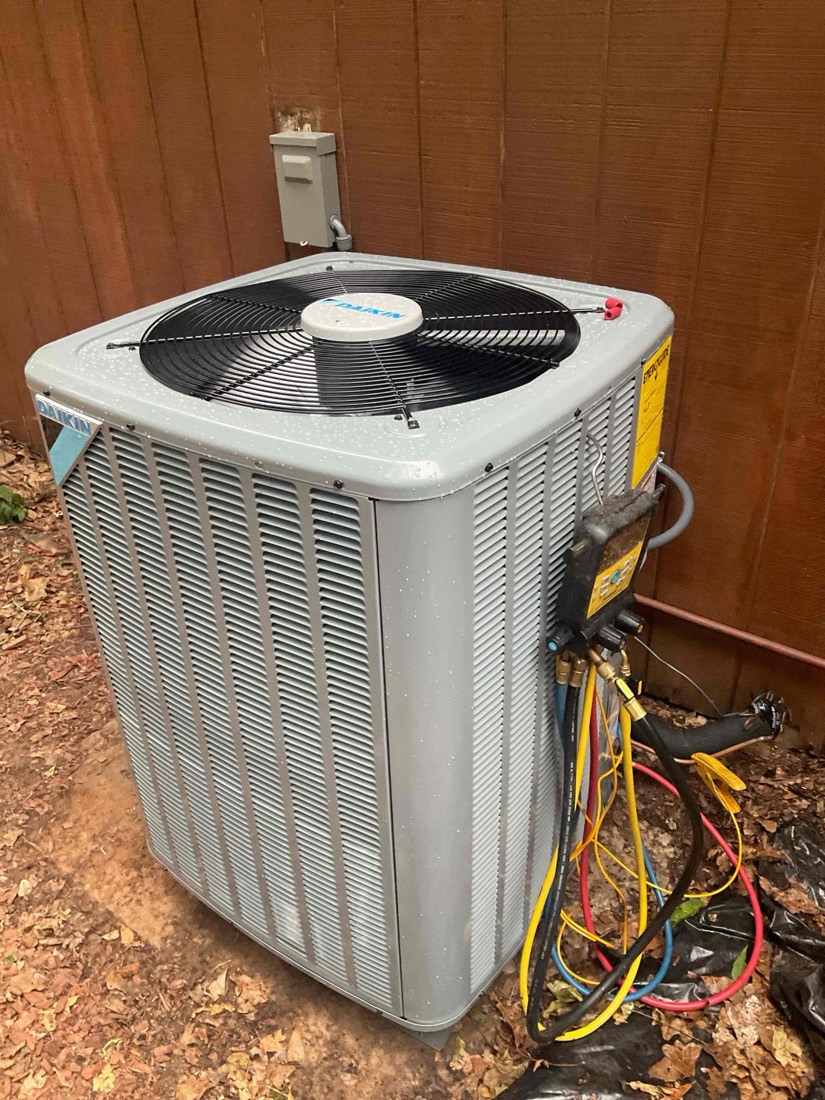 New air conditioning condenser unit installed outdoors with bright white casing and black fan.