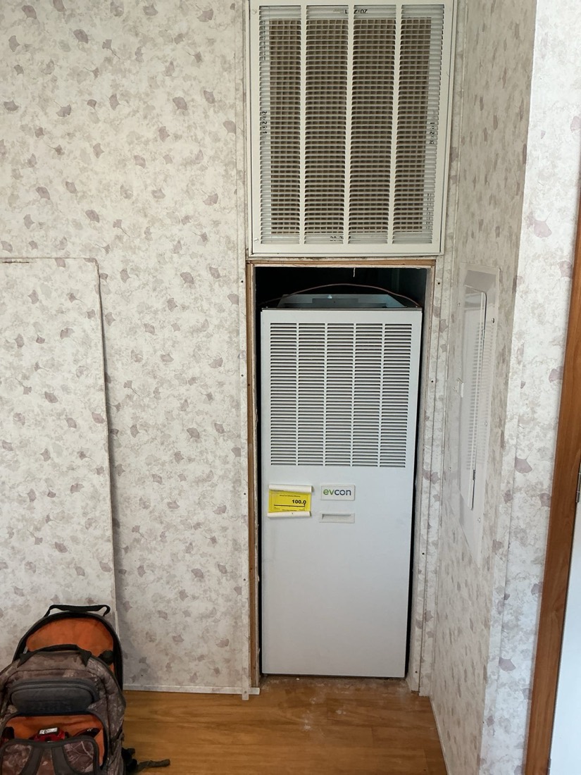 Installed evaporative cooler unit with upper ductwork and intake grille in place.