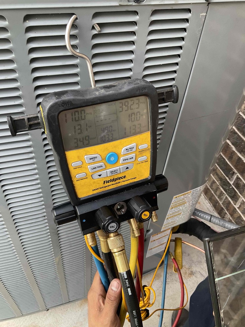 Technician using manifold gauge set on AC condenser unit