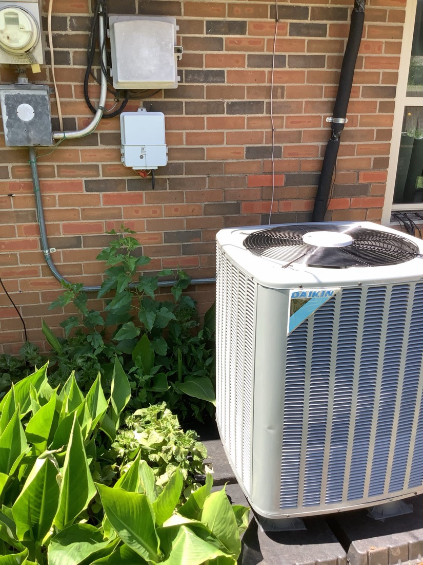 Daikin AC unit installed against brick exterior with wiring