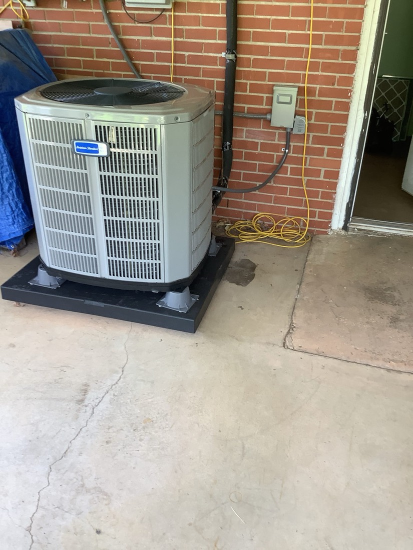 New air conditioning condenser unit installed on concrete base.