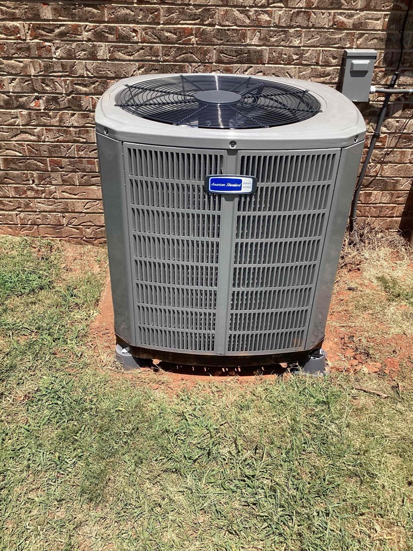 Newly installed AC condenser unit against brick wall