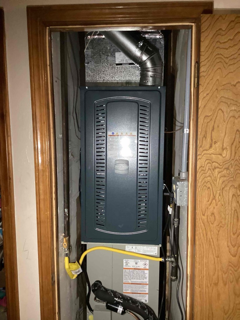 Furnace and air handler installed in closet with ductwork visible at top