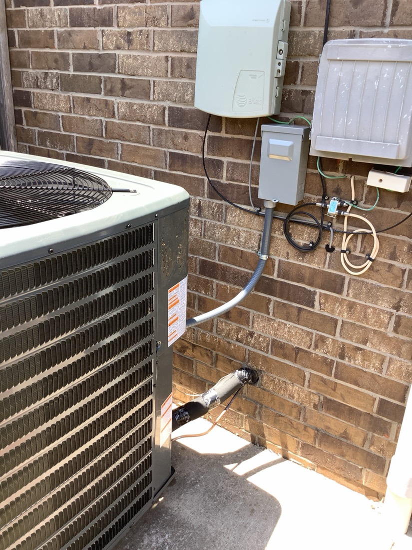 Installed HVAC air handler and condenser unit at brick home exterior