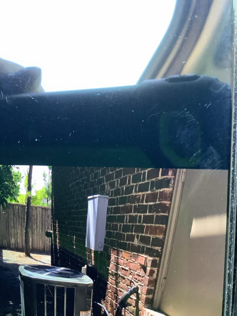 Outdoor HVAC condenser unit mounted against brick wall with disconnect switch.