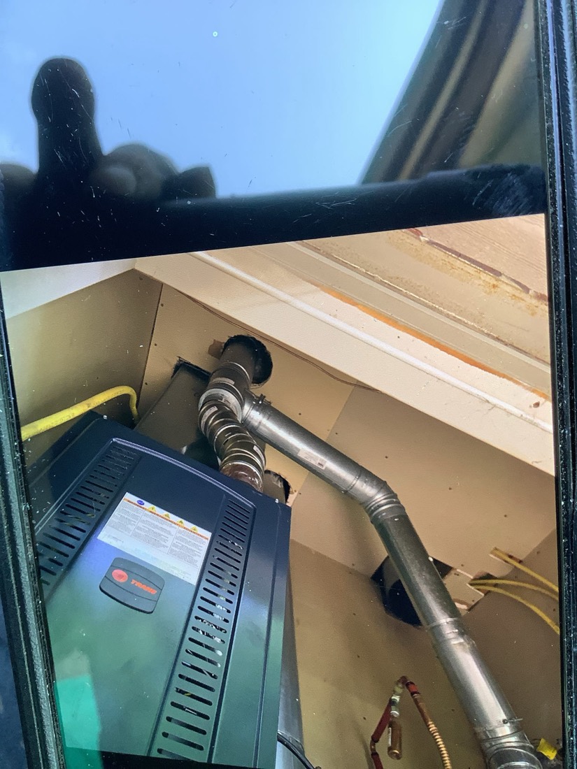 HVAC furnace unit with connected copper tubing and ductwork in attic installation.