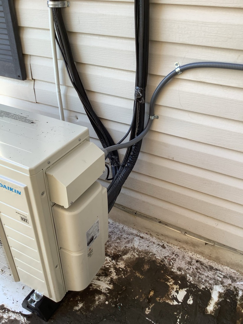 Daikin mini split condenser with connected refrigerant lines.
